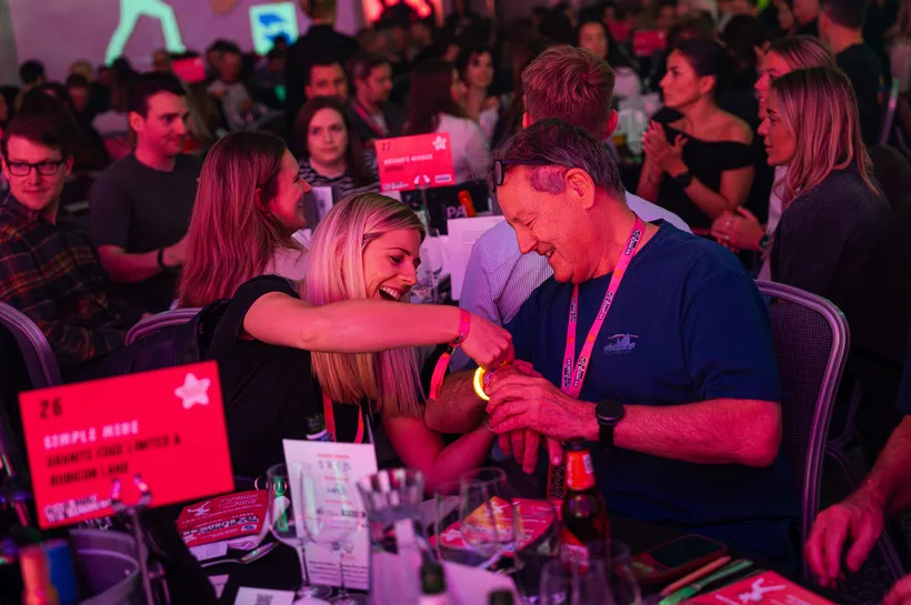 women putting a wrist band on a man in a busy room