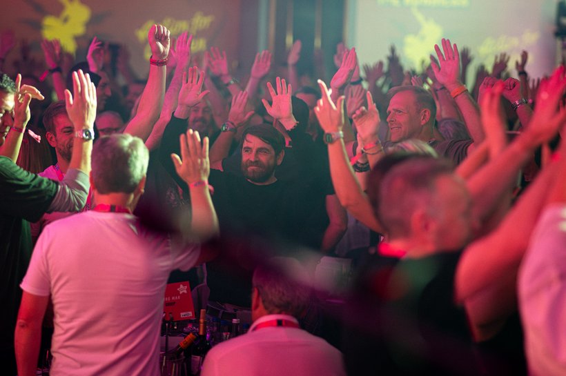 a room full of people with they're hands in the air