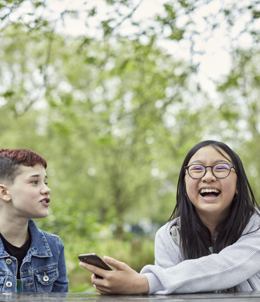 Image of two young people laughing in a park