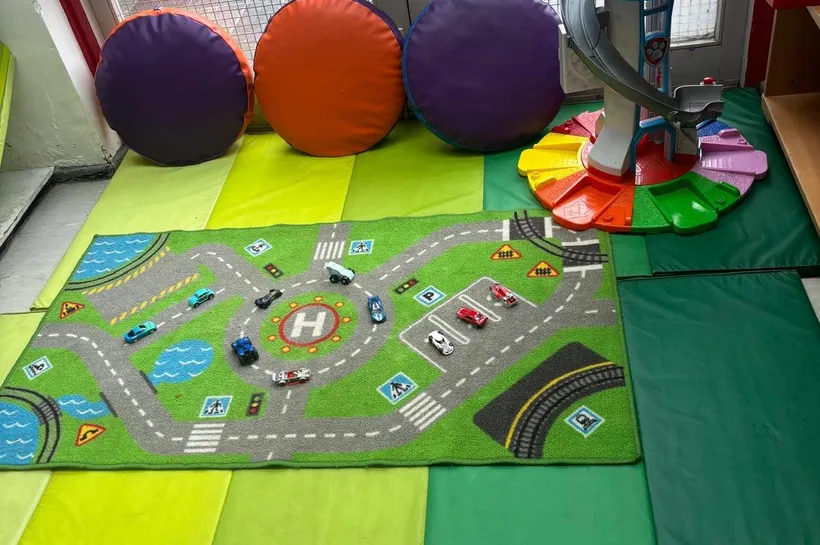 Green crash mats, a rug with roads and cars on, and comfy looking cushions