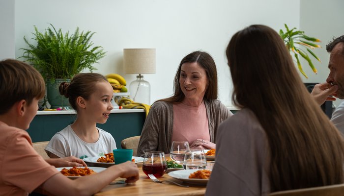 Friendly family dinner with two foster siblings, reflecting belonging and stability in England