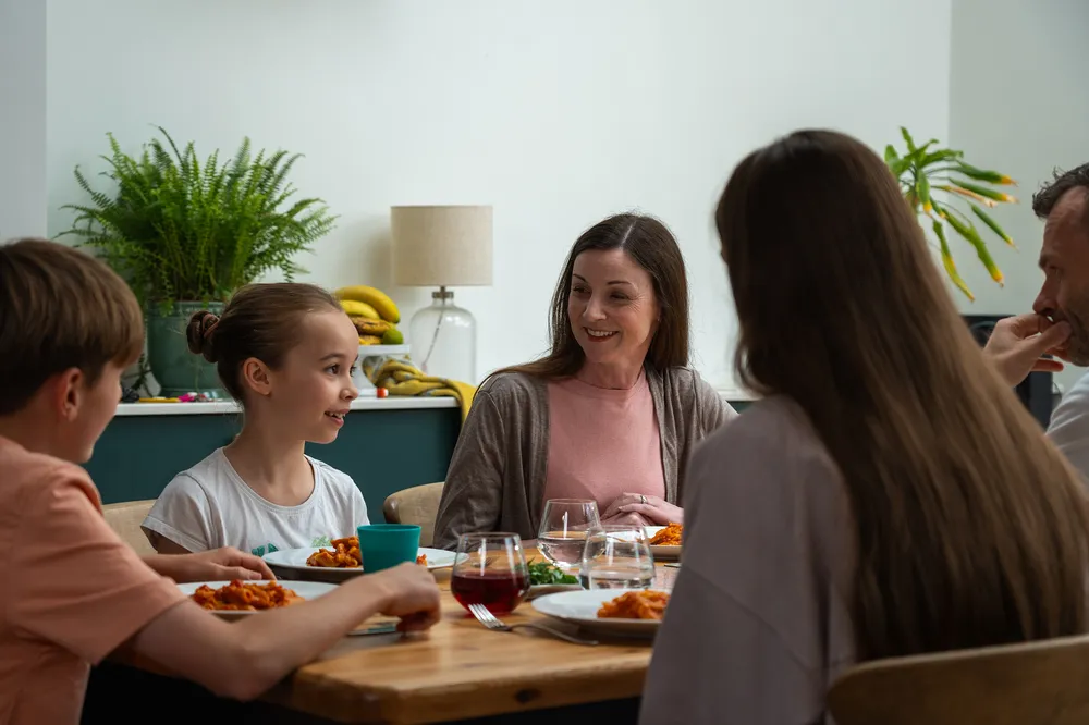 Friendly family dinner with two foster siblings, reflecting belonging and stability in England