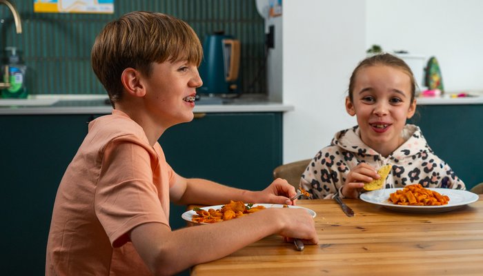Two children sharing a laugh over lunch, reflecting a warm and relaxed family atmosphere