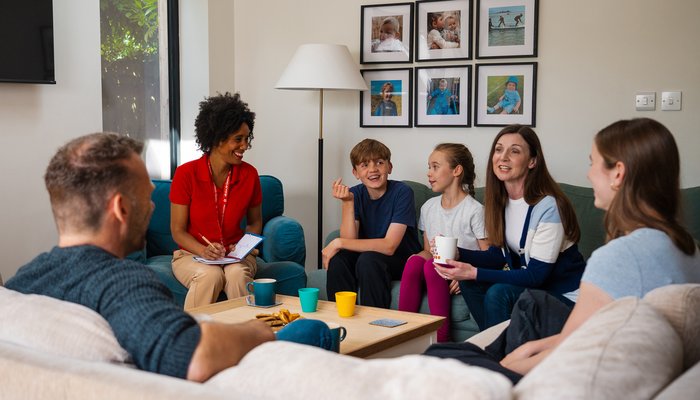 Extended family meeting with a social worker over tea, reflecting open and supportive fostering