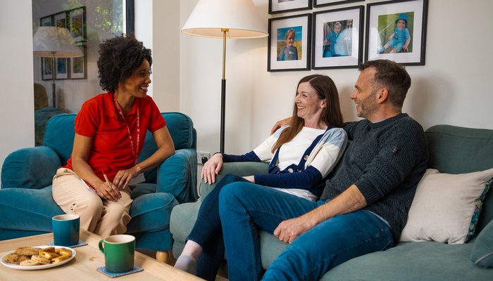 Two foster carers laughing with their social worker, showing trust, connection and genuine support