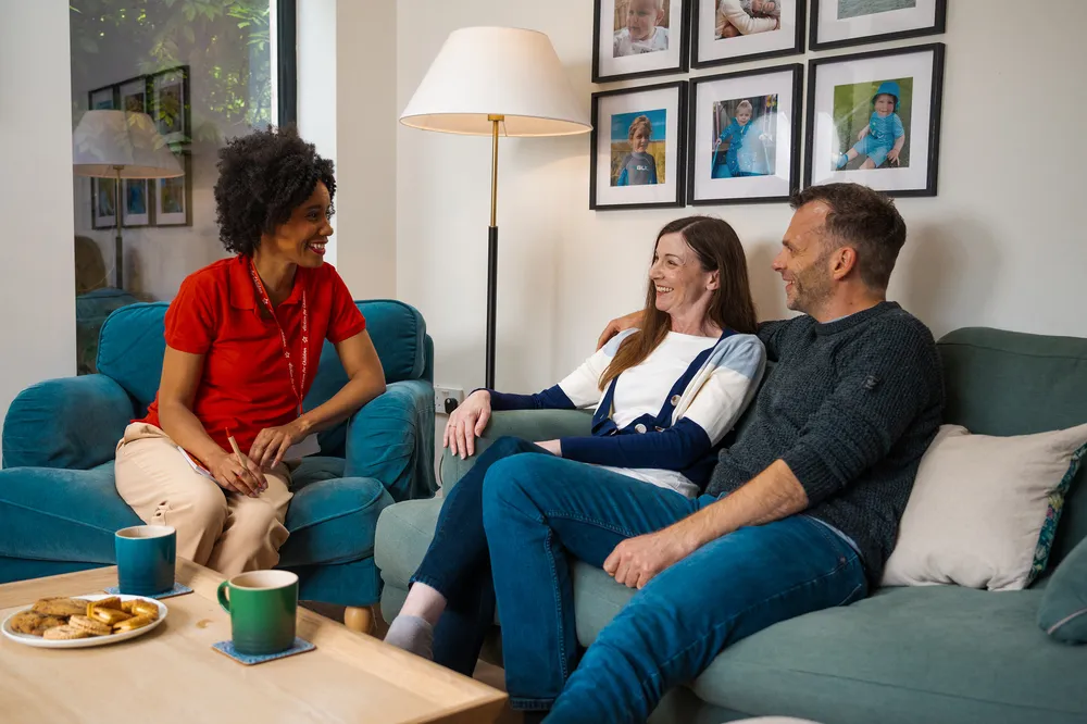 Two foster carers laughing with their social worker, showing trust, connection and genuine support