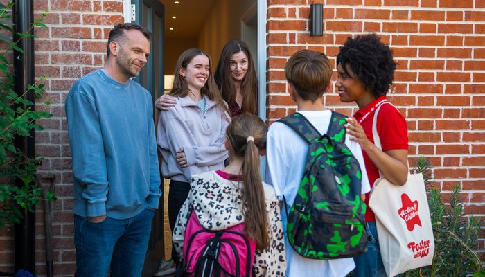 Social worker introducing two siblings to their new foster family during a warm doorstep welcome