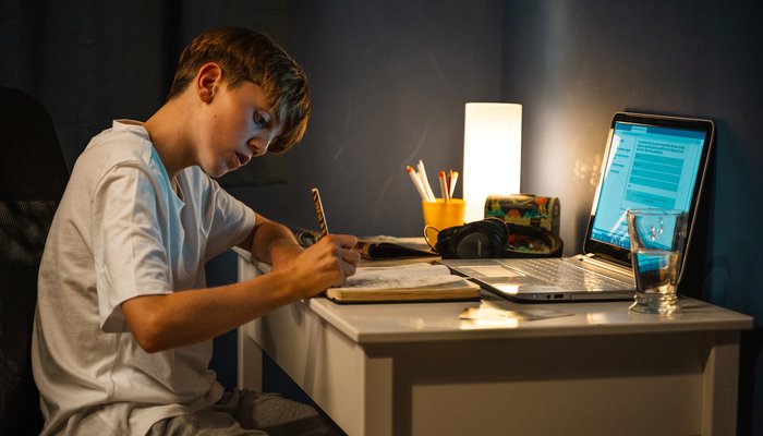 Teenage boy studying at his own desk in his bedroom, showing a space to grow and thrive