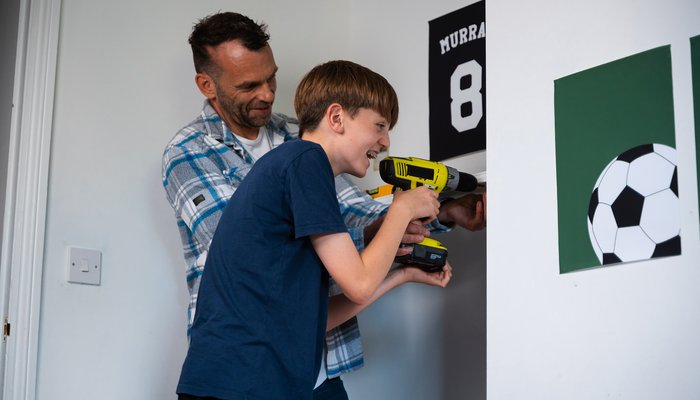 Foster carer teaching a teenage boy DIY skills, showing hands‑on support in Northern Ireland