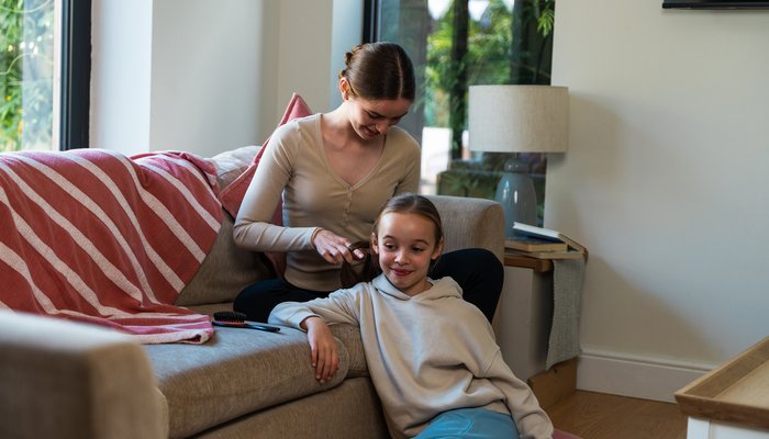 Older teen plaiting a younger girl’s hair, showing nurturing relationships in foster families