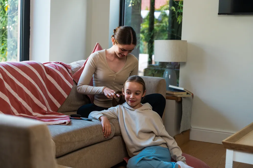Older teen plaiting a younger girl’s hair, showing nurturing relationships in foster families