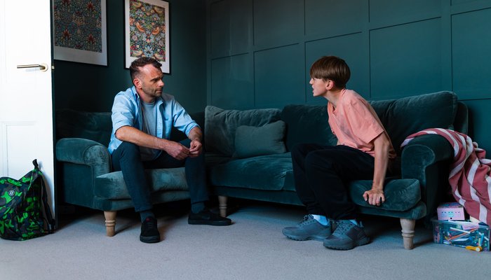 Foster carer listening patiently to an upset teenage boy during a challenging moment