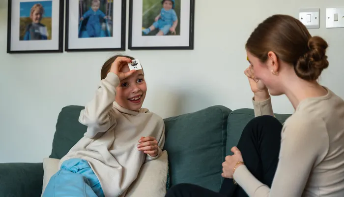 Two children smiling and playing a game on the sofa, showing a nurturing foster home atmosphere