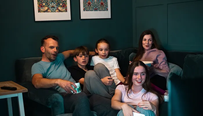 Family watching TV together with two sibling foster children, showing everyday life in fostering in Wales