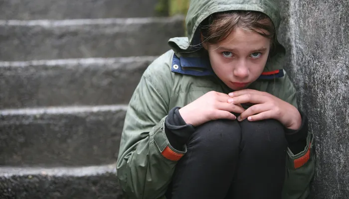 Young teen girl sitting on the steps in the cold with eye contact