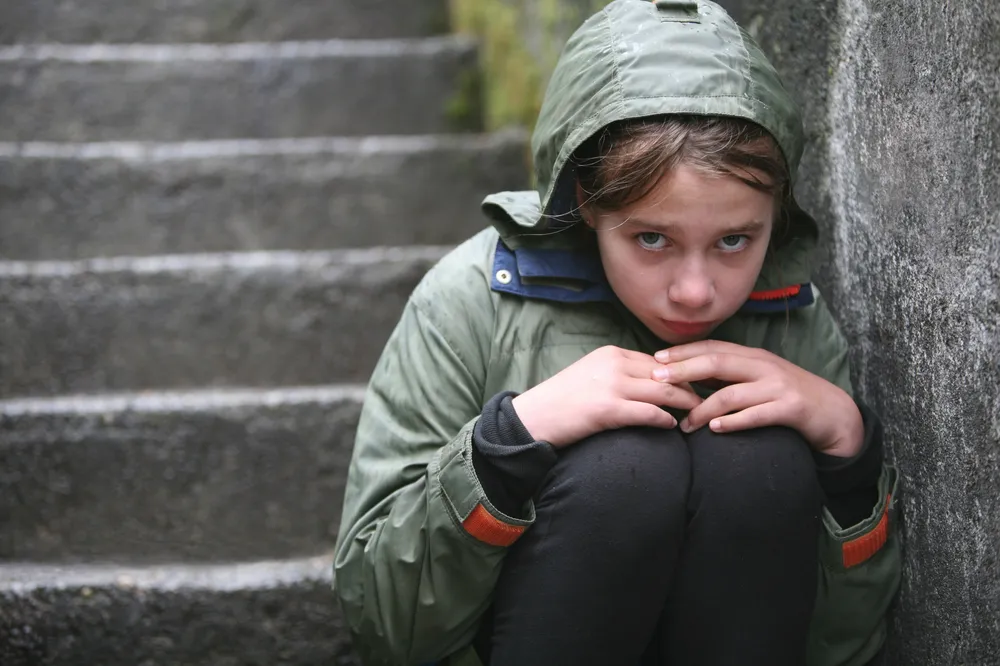 Young teen girl sitting on the steps in the cold with eye contact