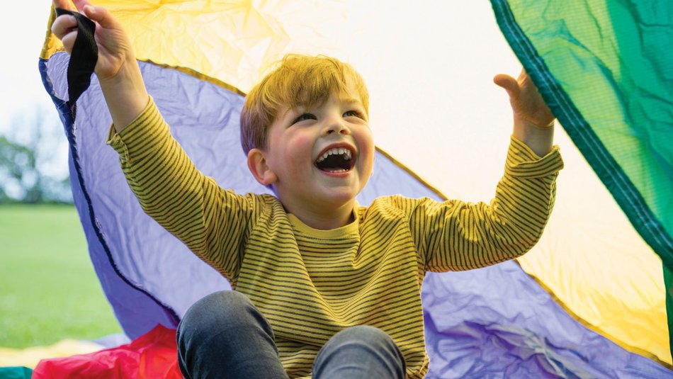 A young child playing outside with a parachute