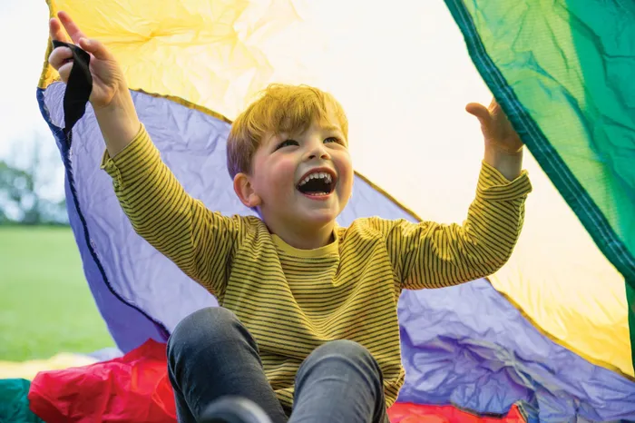 A young child playing outside with a parachute