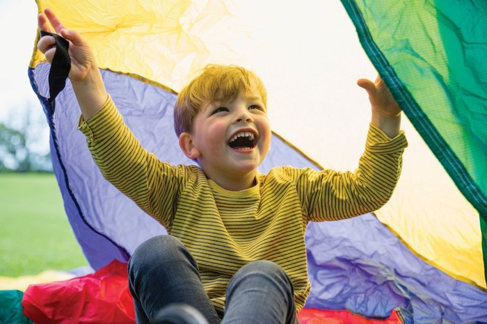 A young child playing outside with a parachute