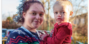 Woman holding little girl wearing a Christmas jumper