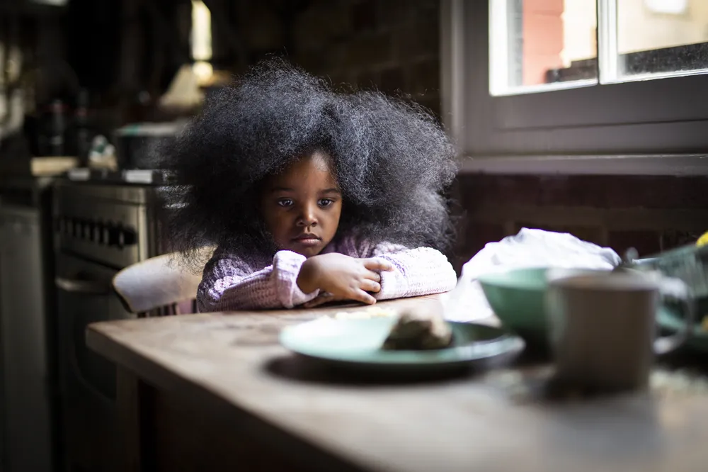 Alice a hunry sad girl sits at a table looking at empty plates
