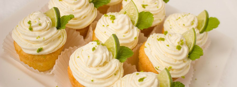 Close up of cupcakes decorated with lime wedges and mint leaves