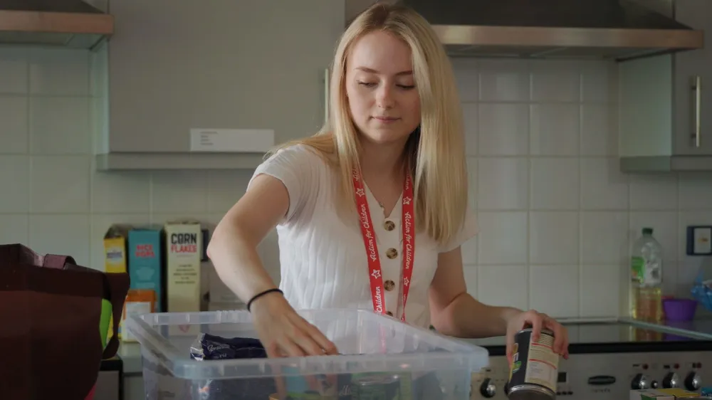 Courtney placing tinned food into a clear box