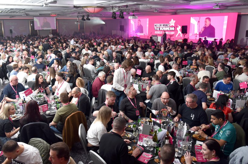 large room filled with people looking at a stage