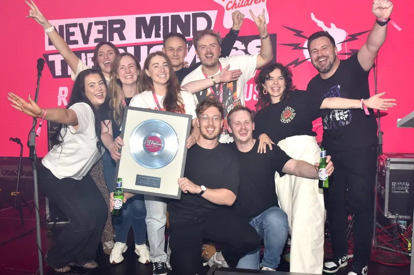 a group of people on a stage holding a frame with a silver record on it