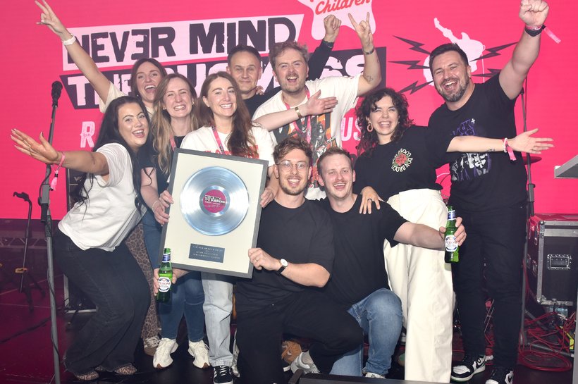 five females and five males standing on the stage holding a frame with a record in it.