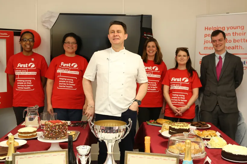 First group staff members stand next to their baking competion entries