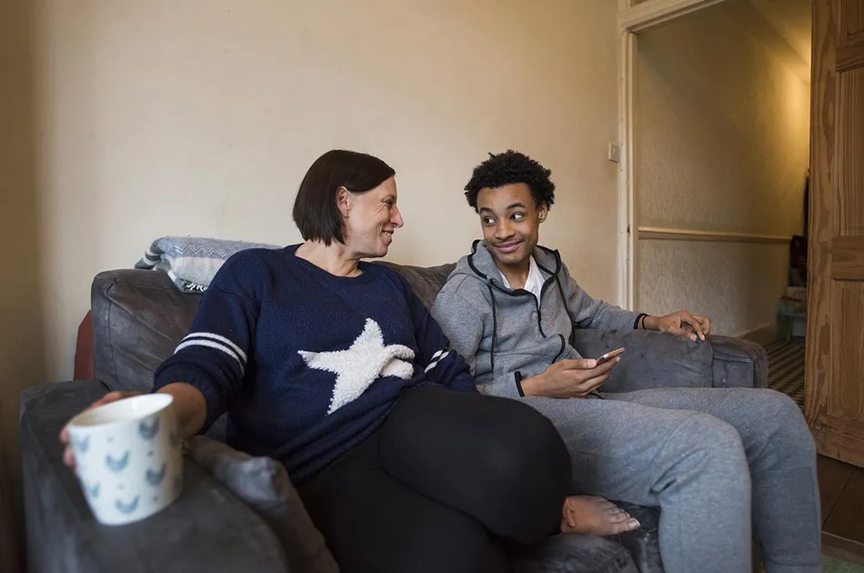 Foster carer with teenager chatting on a couch