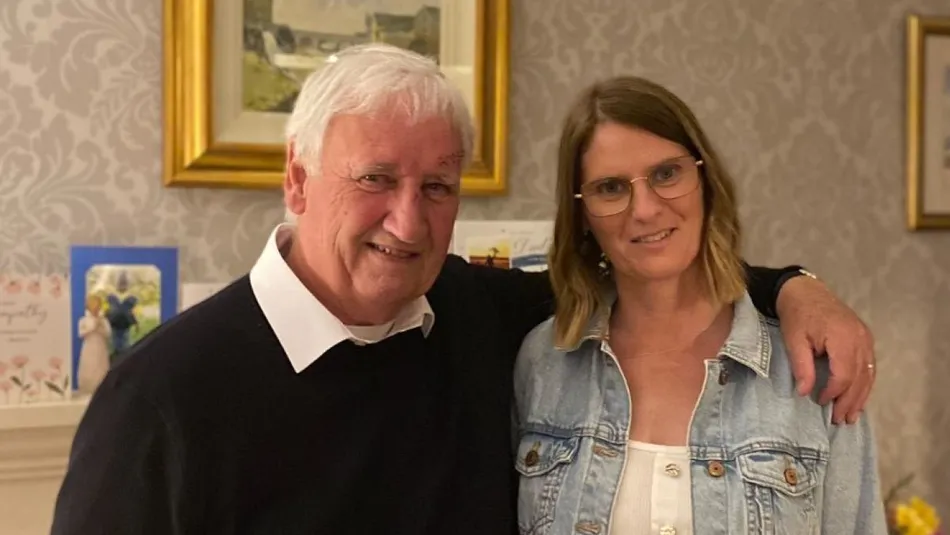 Foster parent Karen and her father Sam stood in living room together and smiling 2