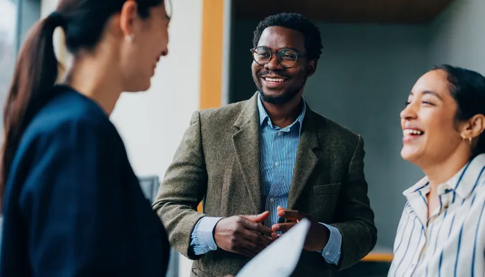Man wearing glasses and two women smiling in office