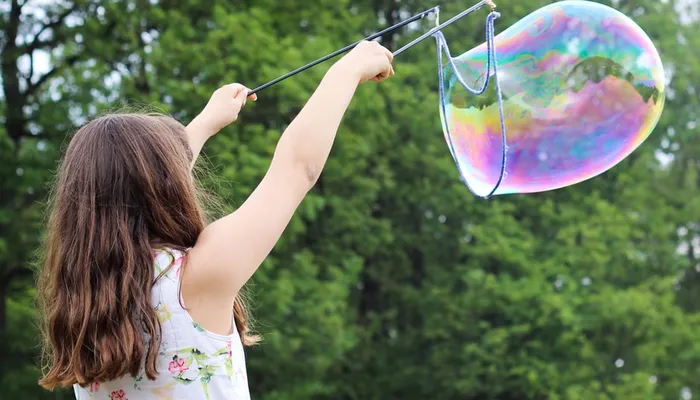 Girl with long hair creating a large bubble in the air