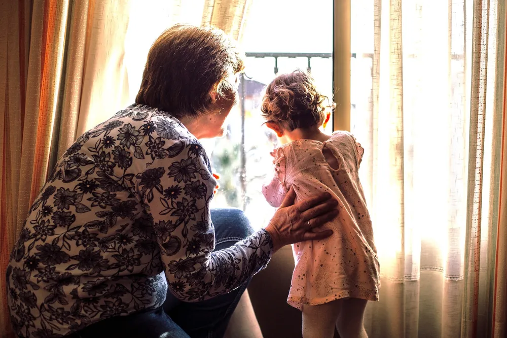 Grandma and grandchild looking out window.