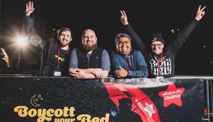 Group of men smiling above Boycott your Bed poster at Boycott your Bed's Leeds event