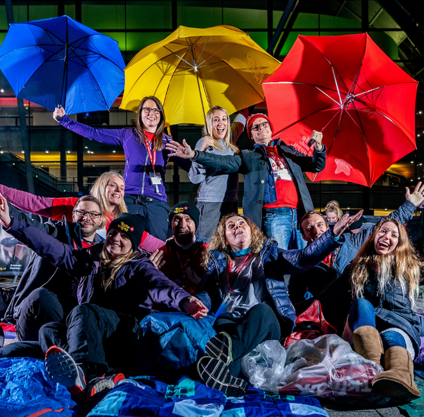 Group of people at Byte Night event. They are outside, Smiling and laughing and are surrounded by sleeping bags and umbrellas
