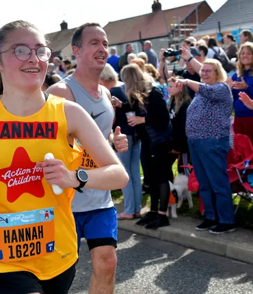 Hannah in a yellow Action for Children running vest at the Great North Run