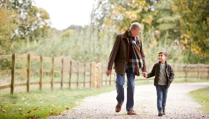 Happy grandfather and grandson walking together and holding hands