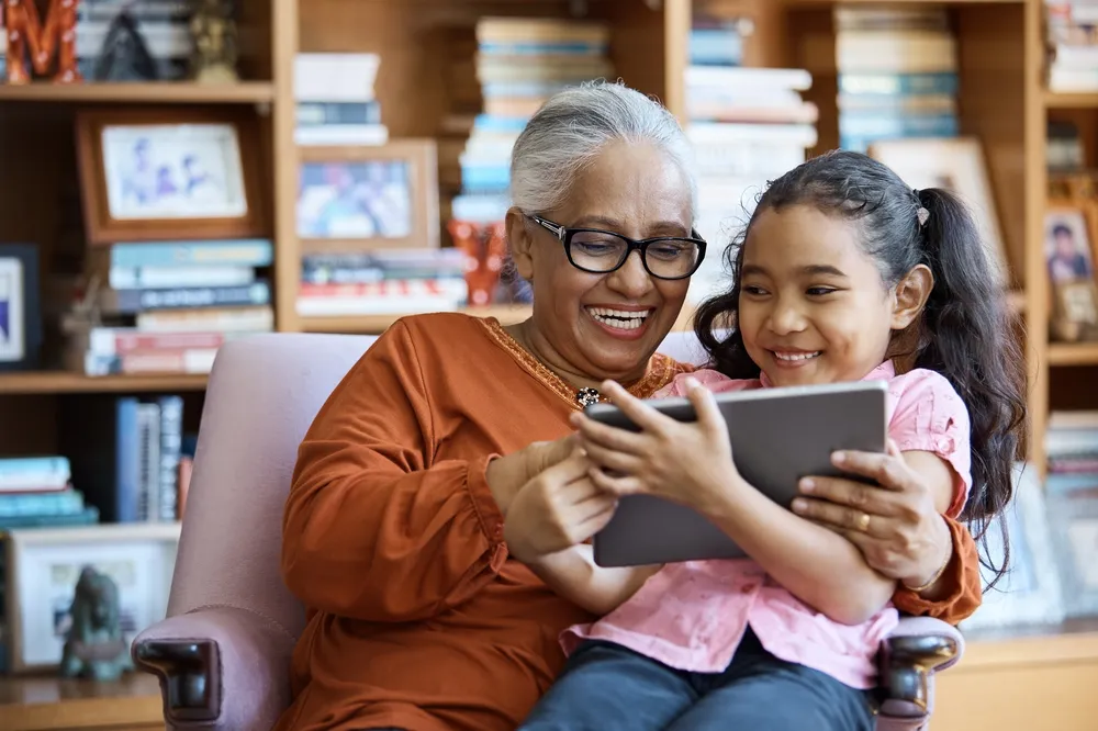Happy mother with daughter on lap using iPad
