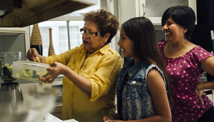 Happy women showing younger girl how to cook in the kitchen.jpg