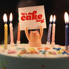 It's cake day piglet holding sign on birthday cake with candles