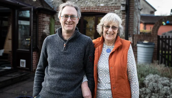 Kelvin and Heather smiling at the camera standing in their garden