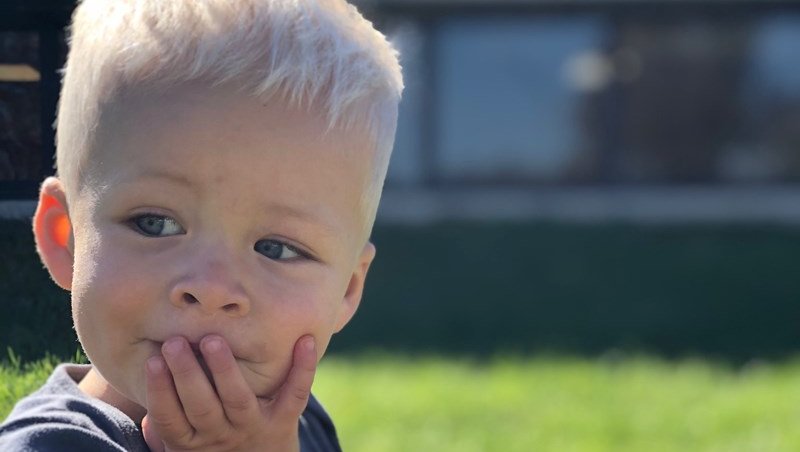 Little boy with hand on his mouth concentrating