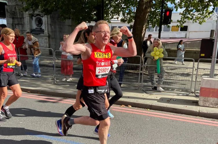 Man running and cheering whilst running the London Marathon for Action for Children