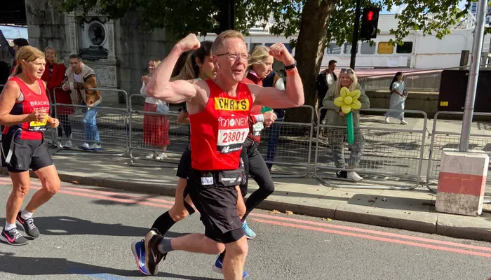 Man running and cheering whilst running the London Marathon for Action for Children