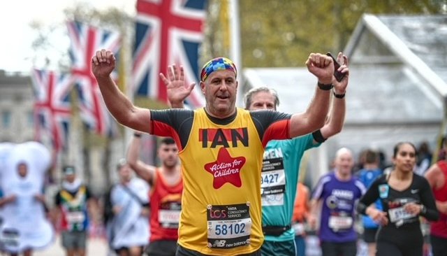 Action for Children runner cheering whilst running down Pall Mall at the London Marathon