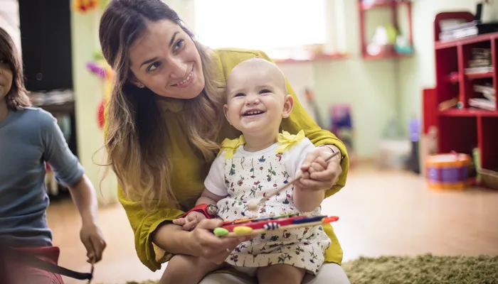 Mother and baby in a playgroup smiling and playing on a xylophone