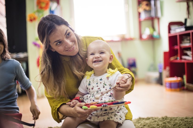 Mother and baby in a playgroup smiling and playing on a xylophone